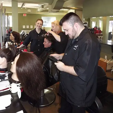A team of hair professionals attending to clients in a busy salon, showcasing various hair styling techniques.