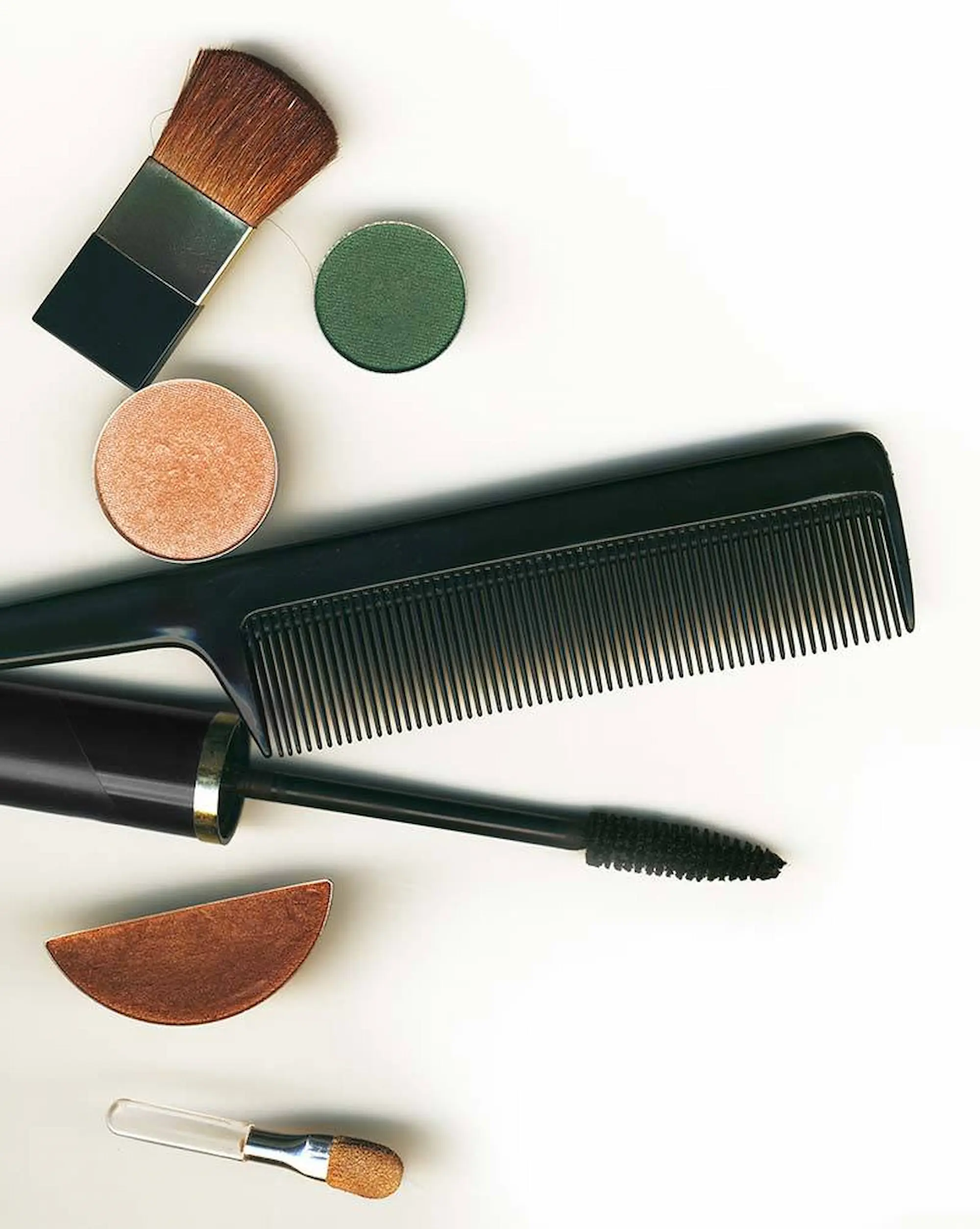 An assortment of makeup brushes, a comb, and makeup items displayed on a clean white background.