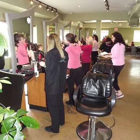 Women in a salon receiving hair services, surrounded by stylists and a lively, colorful environment.